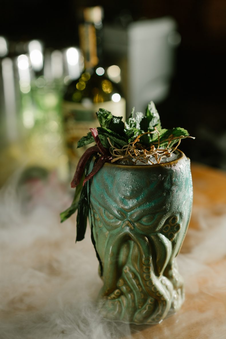 Cocktail in a green tiki mug in a cloud of dry-ice fog