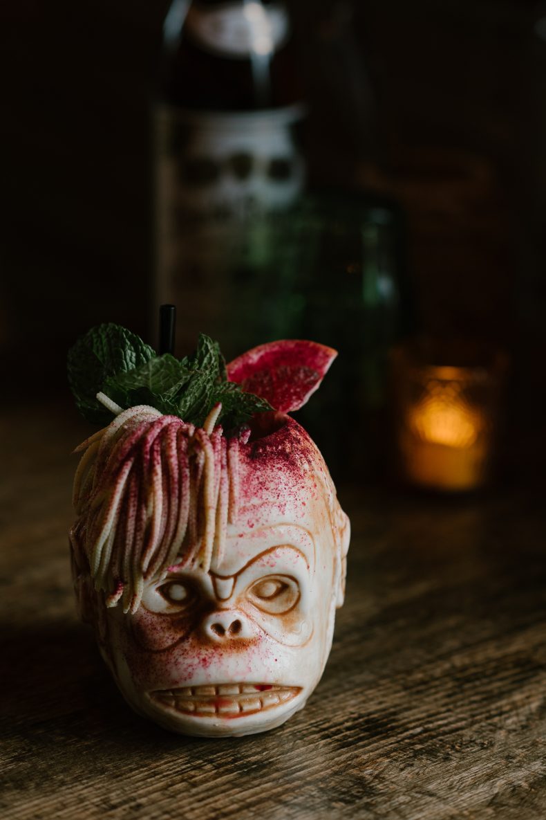 Tiki cocktail in a skull mug with a flower garnish