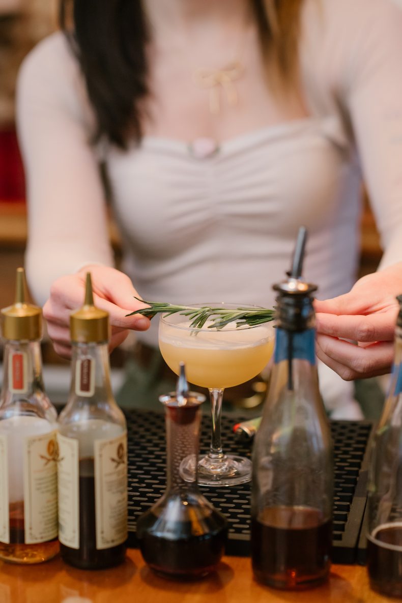Bartender garnishing a cocktail with rosemary