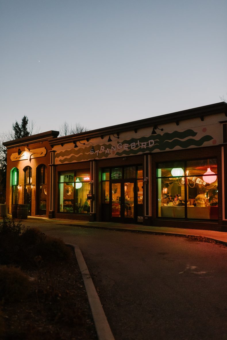 Strange Bird's storefront on Audubon Road at dusk