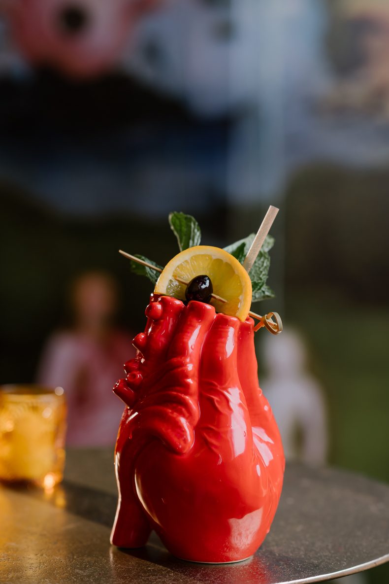 Cocktail in a red anatomical-heart mug with a citrus wheel